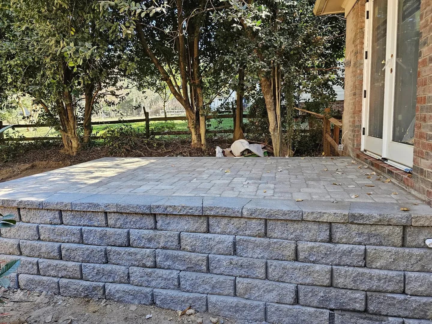Raised Paver Patio at Brick Home by Alex's Lawnscape in Charlotte NC — Elevated paver patio with retaining wall block base adjacent to a brick home