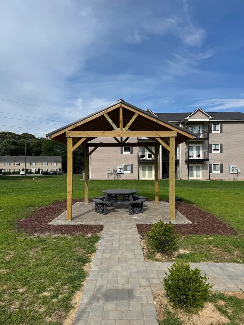 Terraced Retaining Walls & Pergola by Alex's Lawnscape in Charlotte NC — Impressive terraced backyard with paver pathways, retaining wall steps, raised garden beds, and pergola behind a large brick home