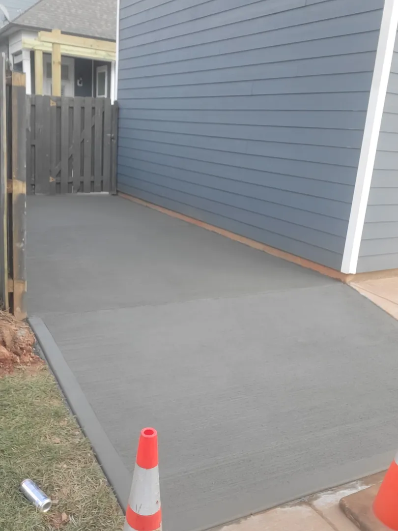Concrete Side Yard Walkway by Alex's Lawnscape in Charlotte NC — Freshly poured and finished concrete pad and walkway along the side of a residential home
